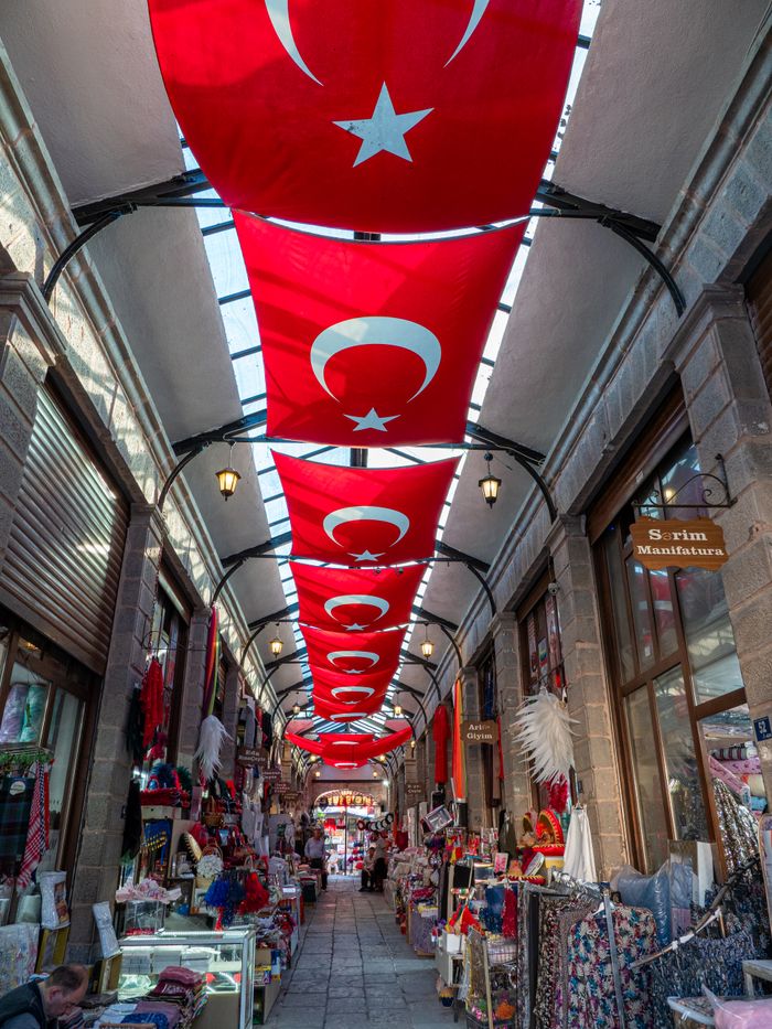 Colorful Turkish bazaar with traditional goods and hanging flags, showcasing vibrant local culture.